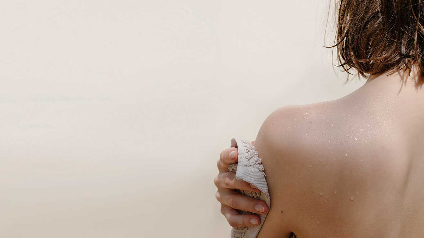Vrouw droogt zich af met handdoek, achteraanzicht. 